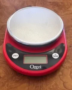 A red digital scale with a bowl on top of it.